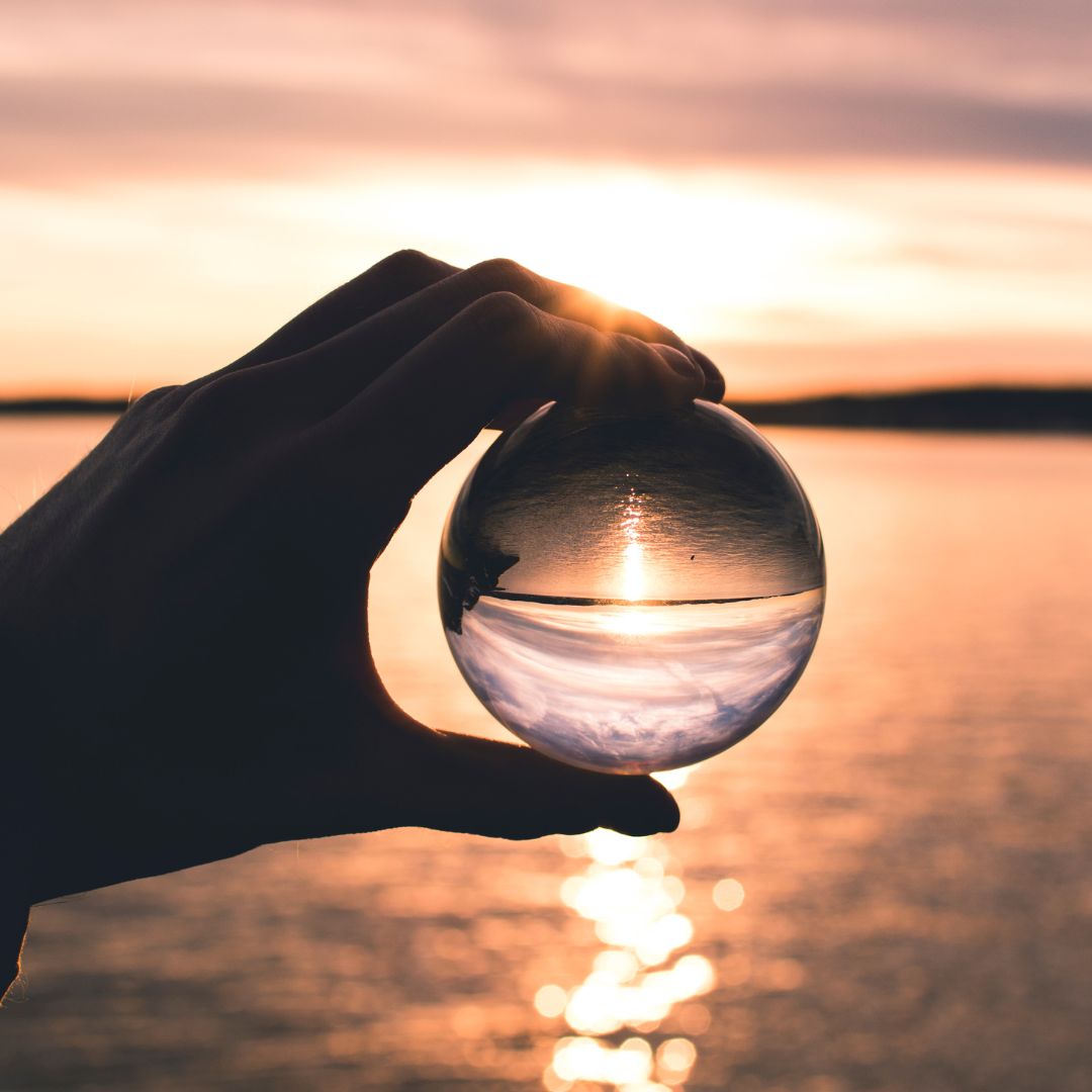 hand with glass sphere at sunset